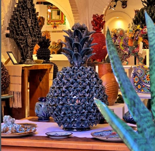 Piña de cerámica negra entre hojas de agave