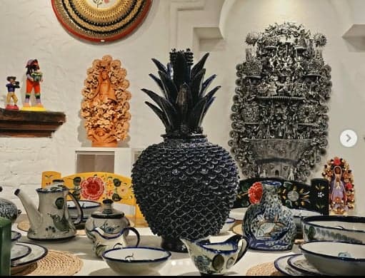Piña de cerámica negra junto a vajilla artesanal sobre mesa de madera