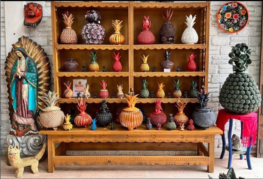 Vitrina de madera tallada con piñas de cerámica vidriada de distintos colores